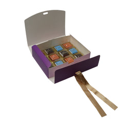 Open box of chocolates with a purple lid on a white surface
